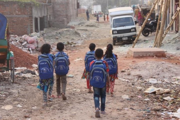 学校から提供されたリュックサックを背負い、悪路を通学する子どもたち