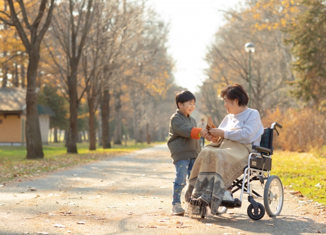 車いすの老人にプレゼントする子ども