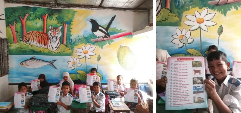 壁画が完成した教室で、関連する教科書を見せてくれる子ども達